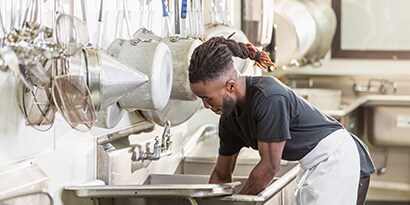 man washing dishes in commercial kitchen
