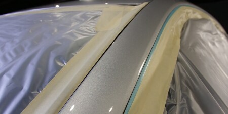 Image of masking film and  tape applied over the windows of an automobile before the paint process
