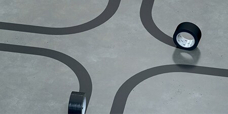 Image of rolls of black 3M™ Vinyl Tape 471 marking four curves where 90-degree angles come together
