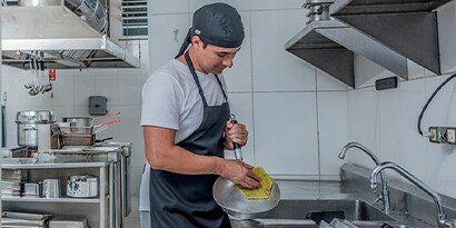 chef cleaning dishes in a full service commercial kitchen
