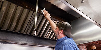 Man cleaning kitchen with degreaser wipe
