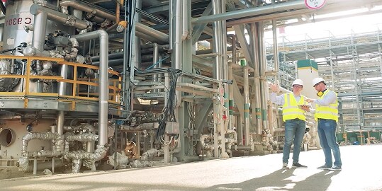two energy experts in safety gear at an industrial facility
