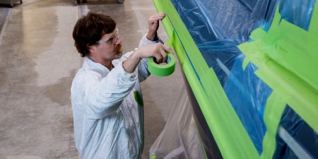 Image of a worker masking off a panel on a boat
