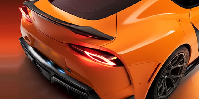Man stretching wrap film over front of car
