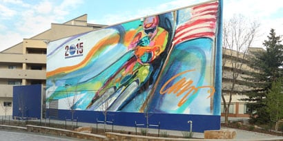 A large outdoor sign featuring a painted image of a bicyclist has bright colors protected by laminated film.
