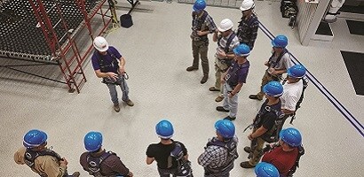 Group of wokers in safety gear gathered around fall protection instructor
