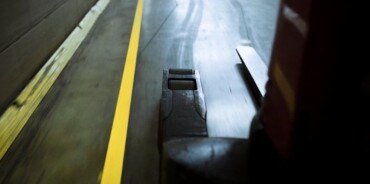 Forklift driving in warehouse marked with floor marking tape.
