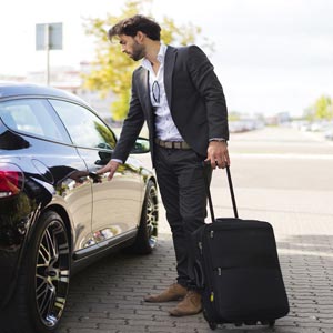 person with a suitcase next to a car
