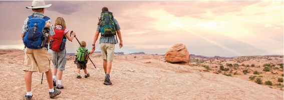 Dad and three kids hike the desert at sunset