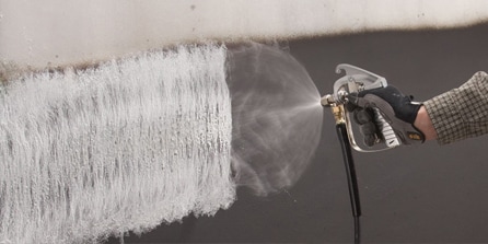 person spraying adhesive with applicator
