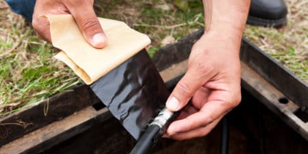 Worker wrapping cable in 3M Vinyl Mastic Pad

