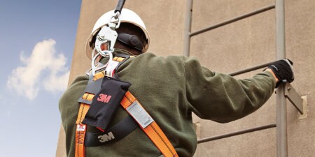 worker climbing up ladder wearing 3M Fall Protection equipement
