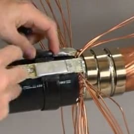 Photo superimposed of hands pulling copper wires back on a 3M Cold Shrink QS-III Joint