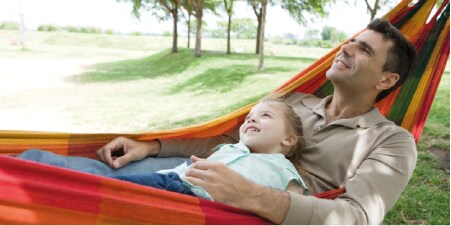 Father and son swing in a hammock and looking at trees
