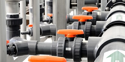A group of pipes with orange handles

