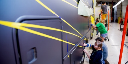 Image of workers masking the side of a recreational vehicle
