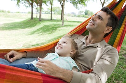 Father and son swing in a hammock and looking at trees