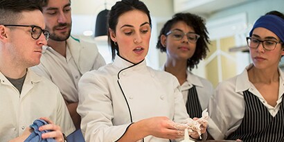 head chef training new employees in commercial kitchen
