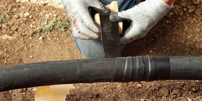 worker wrapping damaged electrical cable in electrical tape
