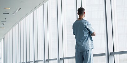 person in scrubs looking out a window
