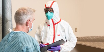 A person in a protective suit and mask talking to a person
