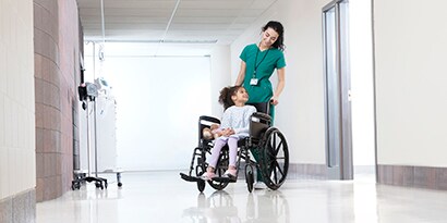 person pushing a child in a wheelchair
