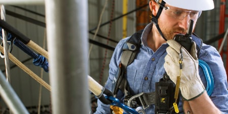 worker in various safety gear on a walkie talkie
