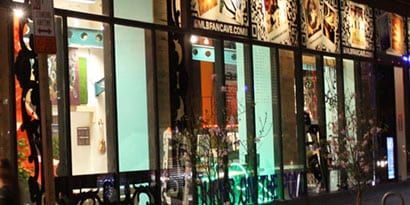 A storefront at nighttime has a bright interior and windows with window graphics.
