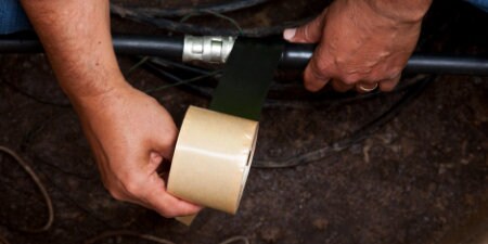 Worker wrapping large cable with 3M Rubber Mastic Tap
