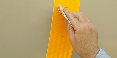 a man's hand applying 3M reflective safety tape 
